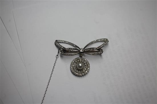 A Belle Epoque platinum and gold, diamond and split pearl set bow brooch with openwork target drop, width 2in.